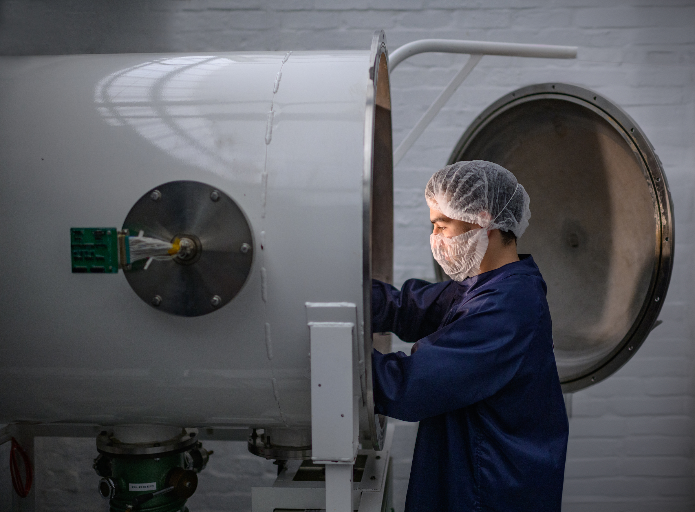 A CubeSpace engineer closing the drum of a testing chamber