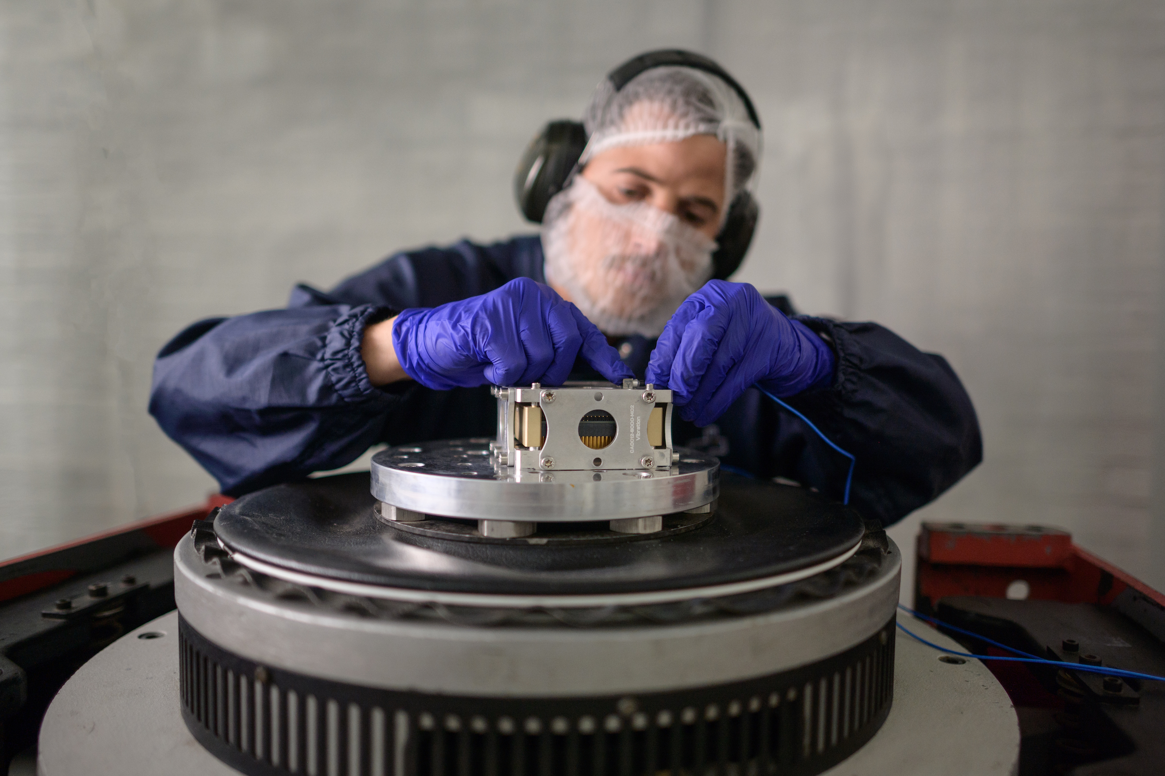 A CubeSpace engineer tapping on the screen of a machine in a darkened room
